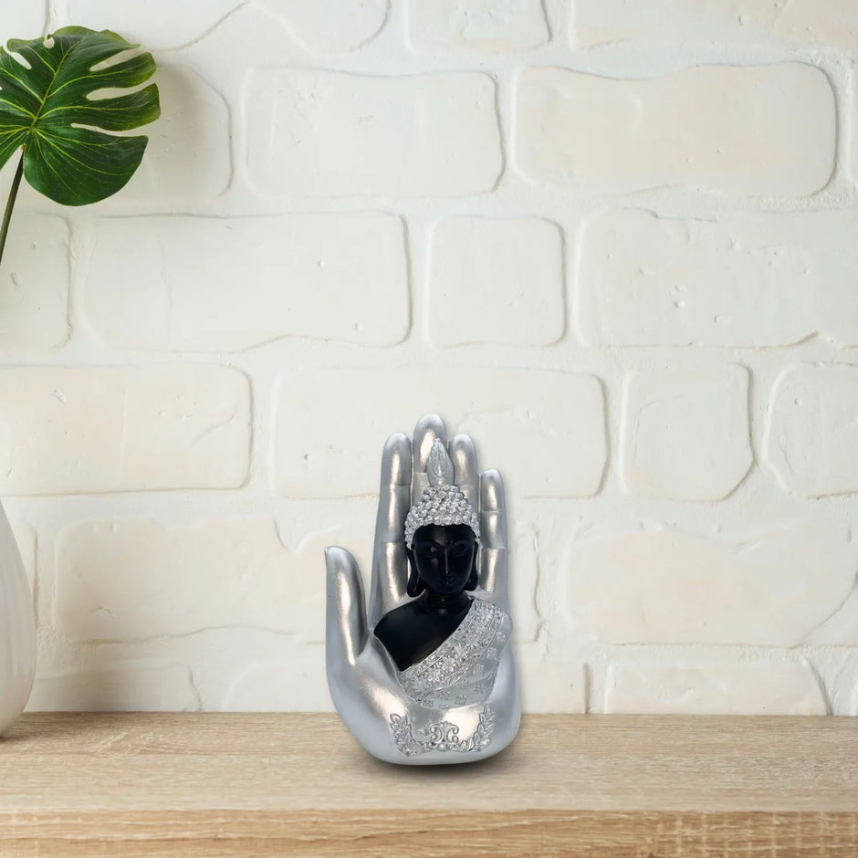 Adorno plateado de una buda sobre una mano